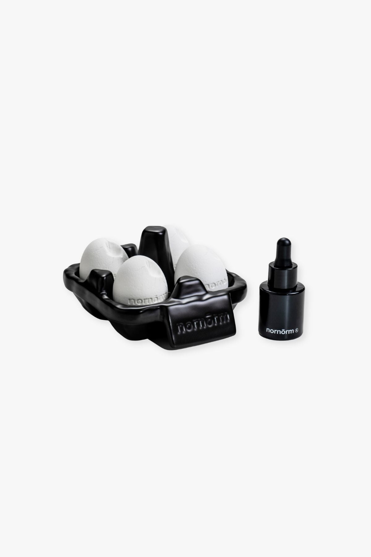 Black egg carton with eggs and a black dropper bottle on a white background