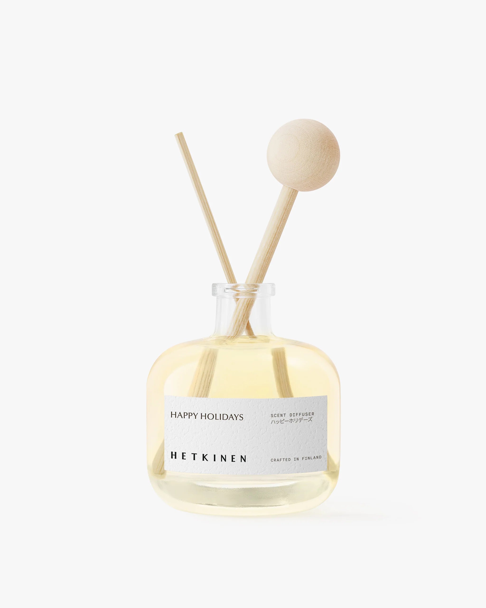 Diffuser bottle with wooden sticks labeled 'Happy Holidays' by 'Hetkinen' on a white background